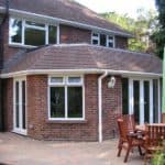 Extended brick house with large windows and outdoor patio.