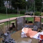 Construction of a backyard brick wall and patio area in progress.