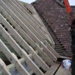 Roof construction with wooden framework and tiled roof in progress.