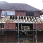 Extension construction on brick house with scaffolding and wooden framework.