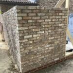 Brick wall of a single-story rear extension under construction in Wrecclesham.