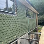 Exterior wall cladding with green scalloped shingles on a residential building.