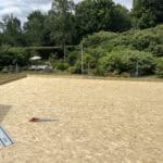 Construction of a new outdoor sports court with wooden surface in a lush garden setting.