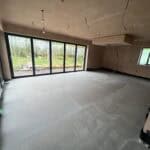 Newly constructed interior space with large glass doors and windows, ready for finishing.