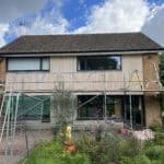 Residential house undergoing exterior renovation with scaffolding and garden in UK.