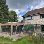 Construction site with scaffolding and fencing around a residential building in the UK.
