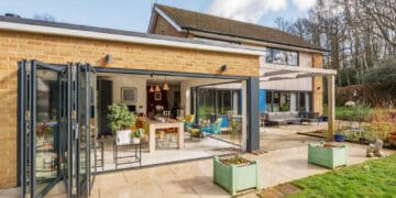 Contemporary glass extension with outdoor patio, garden, and innovative construction by ConstrucTek.