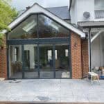 Rear extension with expansive glass panels and pitched roof, enhancing natural light and outdoor vie.