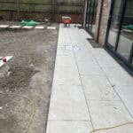 Modern porcelain patio being installed outside a house in Wrecclesham, showcasing durable outdoor pa.