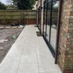 Porcelain patio laid along the house in Wrecclesham, enhancing outdoor space with durable, stylish p.