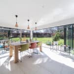 Bright open-plan living space with expansive glass walls and garden outlook, ideal for contemporary.