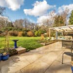 Spacious garden patio with outdoor seating, potted plants, and a glass conservatory, ideal for outdo.