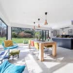 Spacious contemporary kitchen and dining space featuring large glass windows, stylish lighting, and.