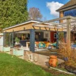 Contemporary glass extension on a residential home with garden and outdoor seating.