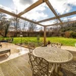 Outdoor patio with garden and wooden pergola for relaxing and entertaining.