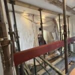 New steel beam being lifted into place on props, with dust sheets protecting the room