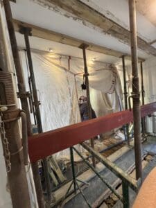 New steel beam being lifted into place on props, with dust sheets protecting the room