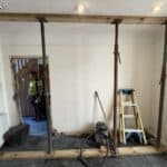 Load-bearing wall propped ready for removal, with dust sheets protecting the house